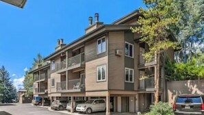 A multi-story residential building with balconies, a garage, and parked cars.