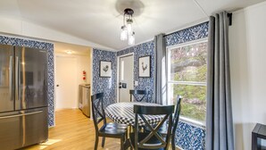 A kitchen with a stainless steel refrigerator, a dining table with chairs, and a window with curtains. - Camp-Style Cabin Near Pigeon Forge: Fire Pit, Deck (Sevierville)