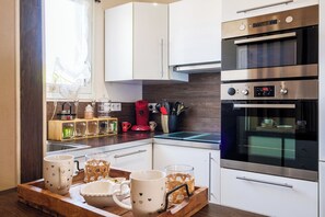 Een moderne keuken met witte kasten, een roestvrijstalen oven en een glazen kookplaat.