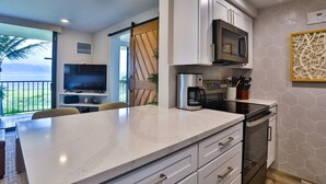 A modern kitchen with a large island, built-in appliances, and a view of the outdoors. - Completely remodeled 2 bedroom King bed AC Kauhale Makai on the top floor (Kihei)