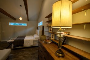 Ein Schlafzimmer mit Bett, Nachttisch, Lampe und Holzregalen.