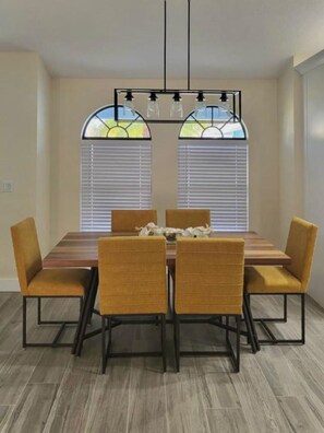 Un comedor con una mesa rectangular, cuatro sillas y una araña.