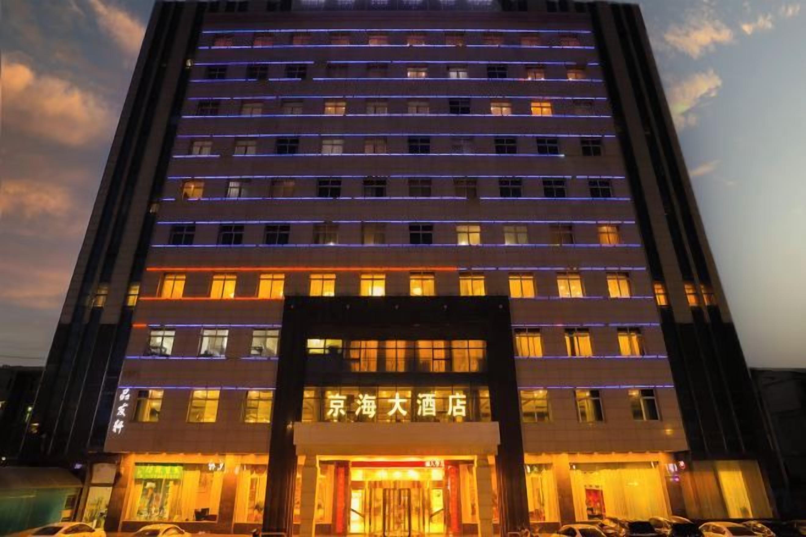 Un hôtel à plusieurs étages, doté de fenêtres illuminées et d’une entrée imposante.