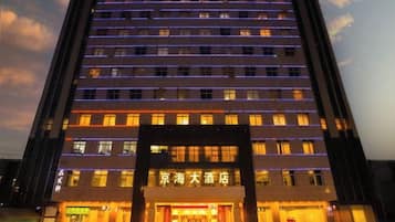 Un hôtel à plusieurs étages, doté de fenêtres illuminées et d’une entrée imposante.