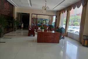 Un hall de hotel con mostrador de recepción, zona de estar y amplios ventanales.