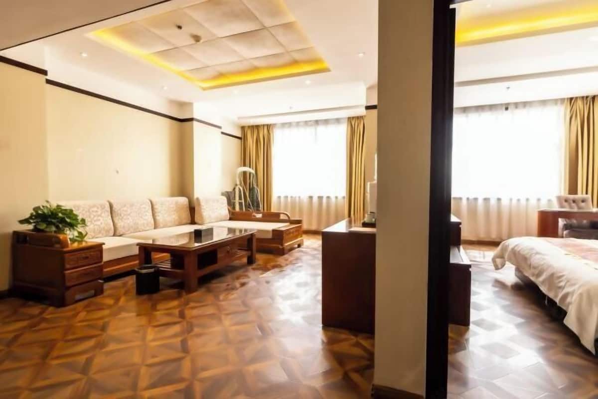 Ein Hotelzimmer mit einer Couch, einem Schreibtisch, einem Bett und einem gemusterten Boden.