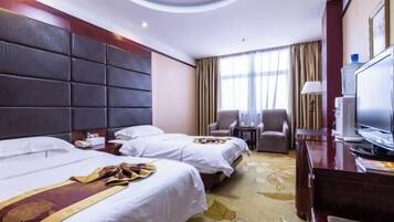 A hotel room with two beds, a desk, a television, and a large window with curtains.