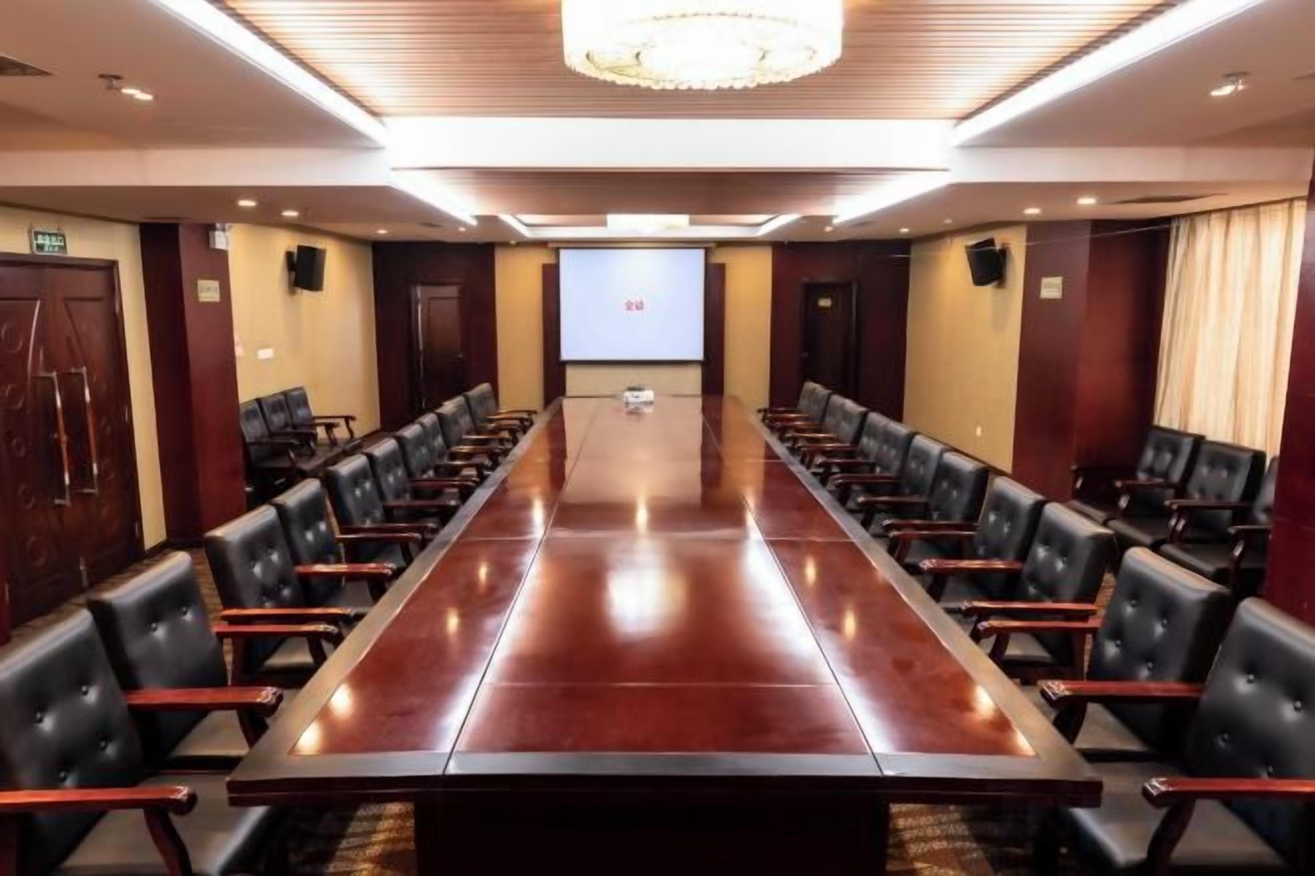 A conference room with a long table and chairs, a projector screen, and a chandelier.