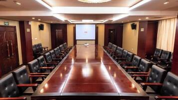 A conference room with a long table and chairs, a projector screen, and a chandelier.