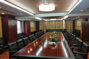 A conference room with a long table, chairs, and a projector.