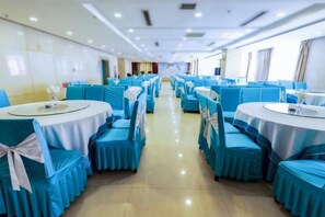 Een feestzaal met ronde tafels en stoelen, gerangschikt in rijen.