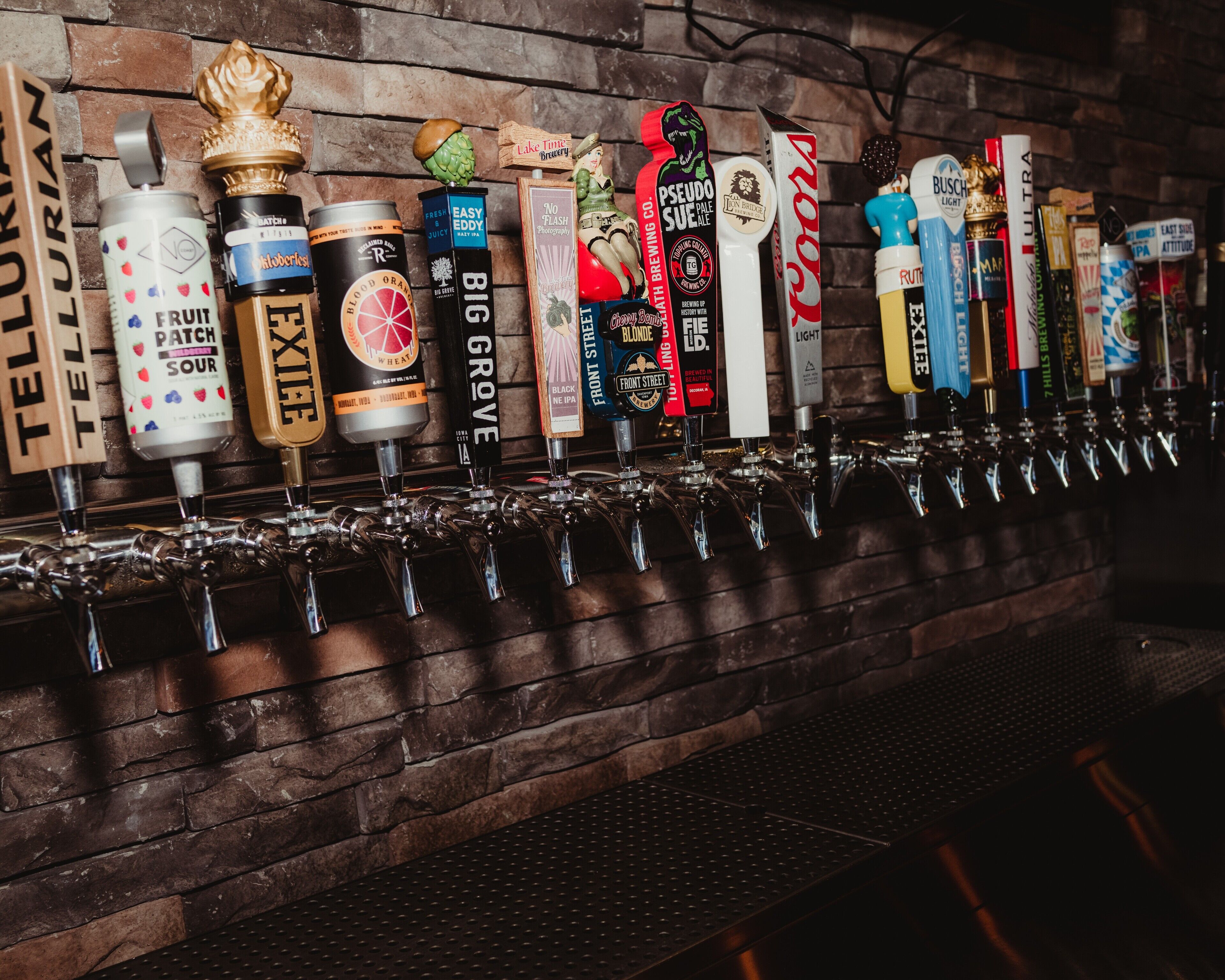 A bar with multiple taps, each labeled with different beer brands.