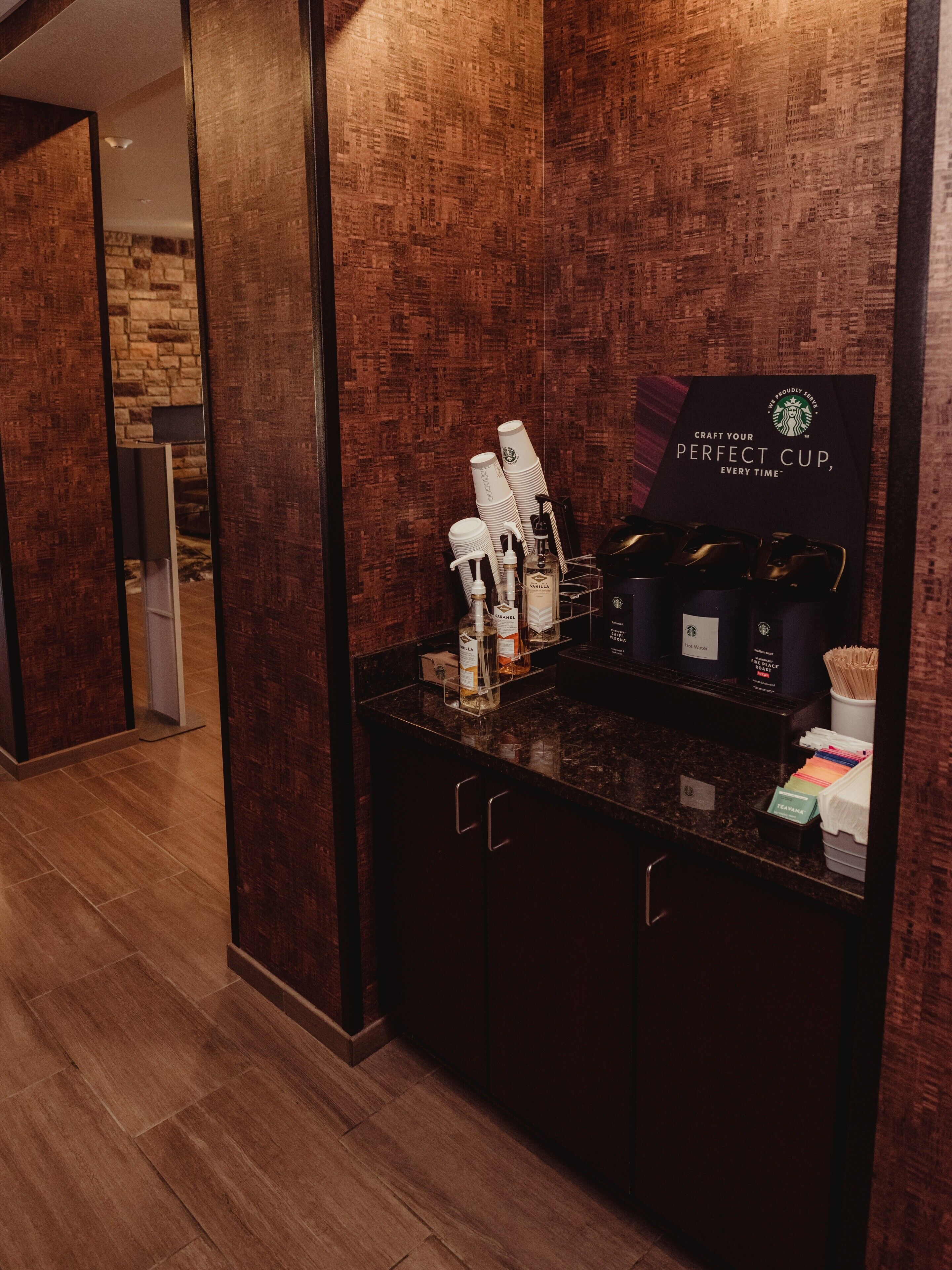 Zona de cafè amb un cartell de Starbucks, una màquina de cafè i diverses tasses i recipients de cafè.