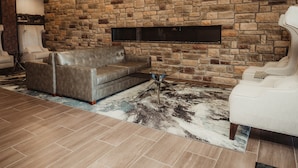 A living room with a stone wall, leather sofa, and two armchairs.
