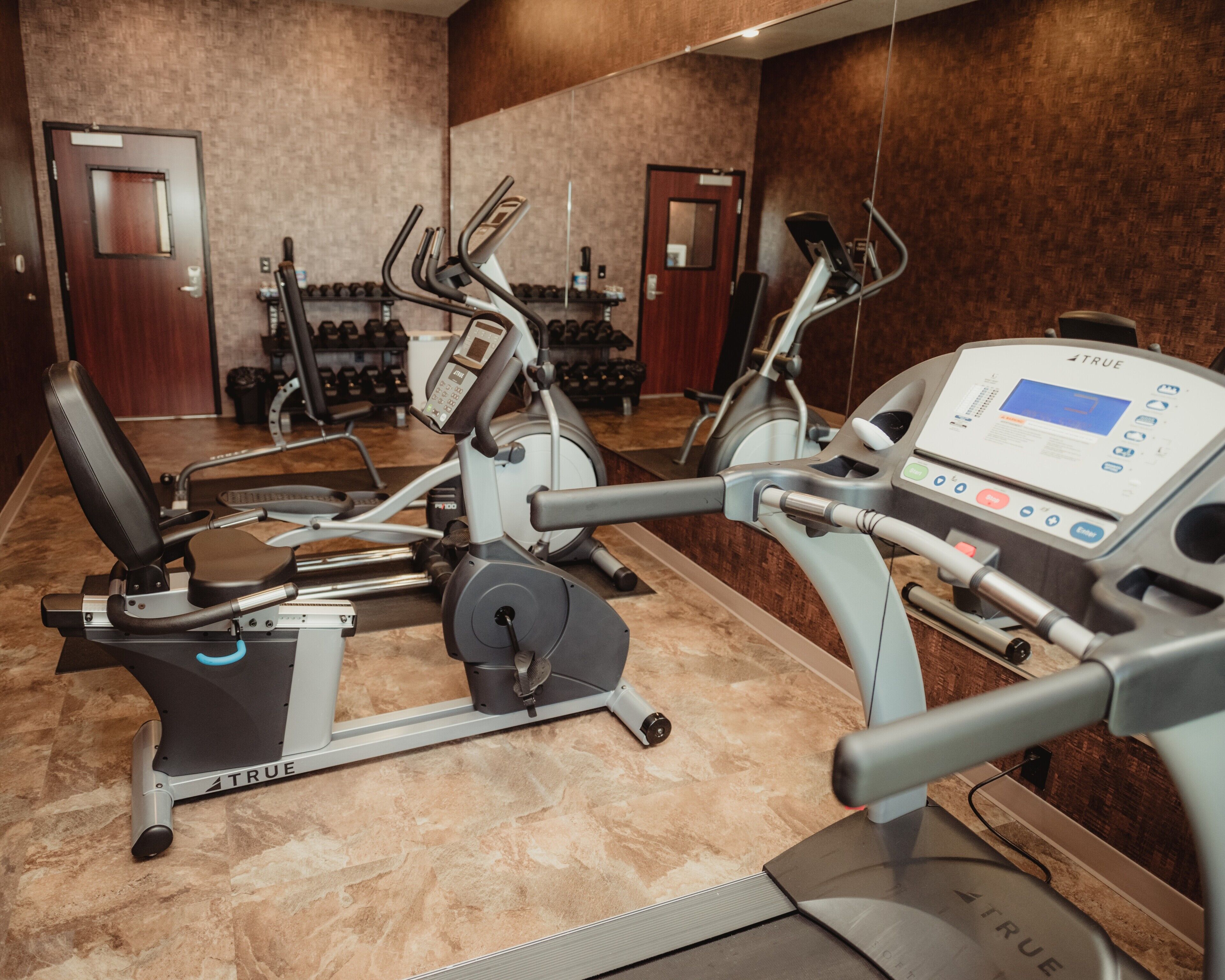 Una palestra con diverse attrezzature per l'allenamento, tra cui tapis roulant e cyclette.