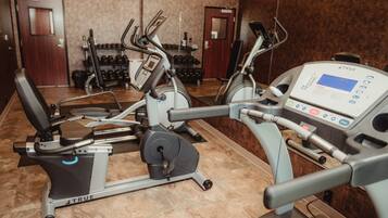 Una palestra con diverse attrezzature per l'allenamento, tra cui tapis roulant e cyclette.