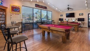 Relax in this modern space with a pool table, TV, and bookshelf, offering a view of the outdoors.