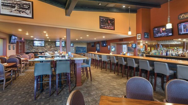 A bar area with multiple seating options, including bar stools and tables, and a counter with a variety of bottles.