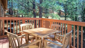 A wooden deck with a table and chairs, surrounded by trees.