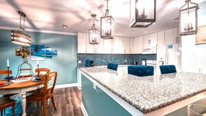 Une cuisine moderne dotée d’un grand îlot central, de luminaires suspendus et d’un mur d’accent bleu.