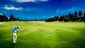 Un terrain de golf avec un ciel dégagé et des arbres en arrière-plan.