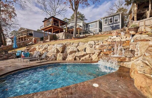 Relax by the pool surrounded by a natural rock waterfall and lounge chairs on the patio.