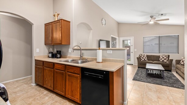 A modern kitchen with wooden cabinets, a dishwasher, and a countertop with a coffee maker. - Your Home away from Home (Goodyear)