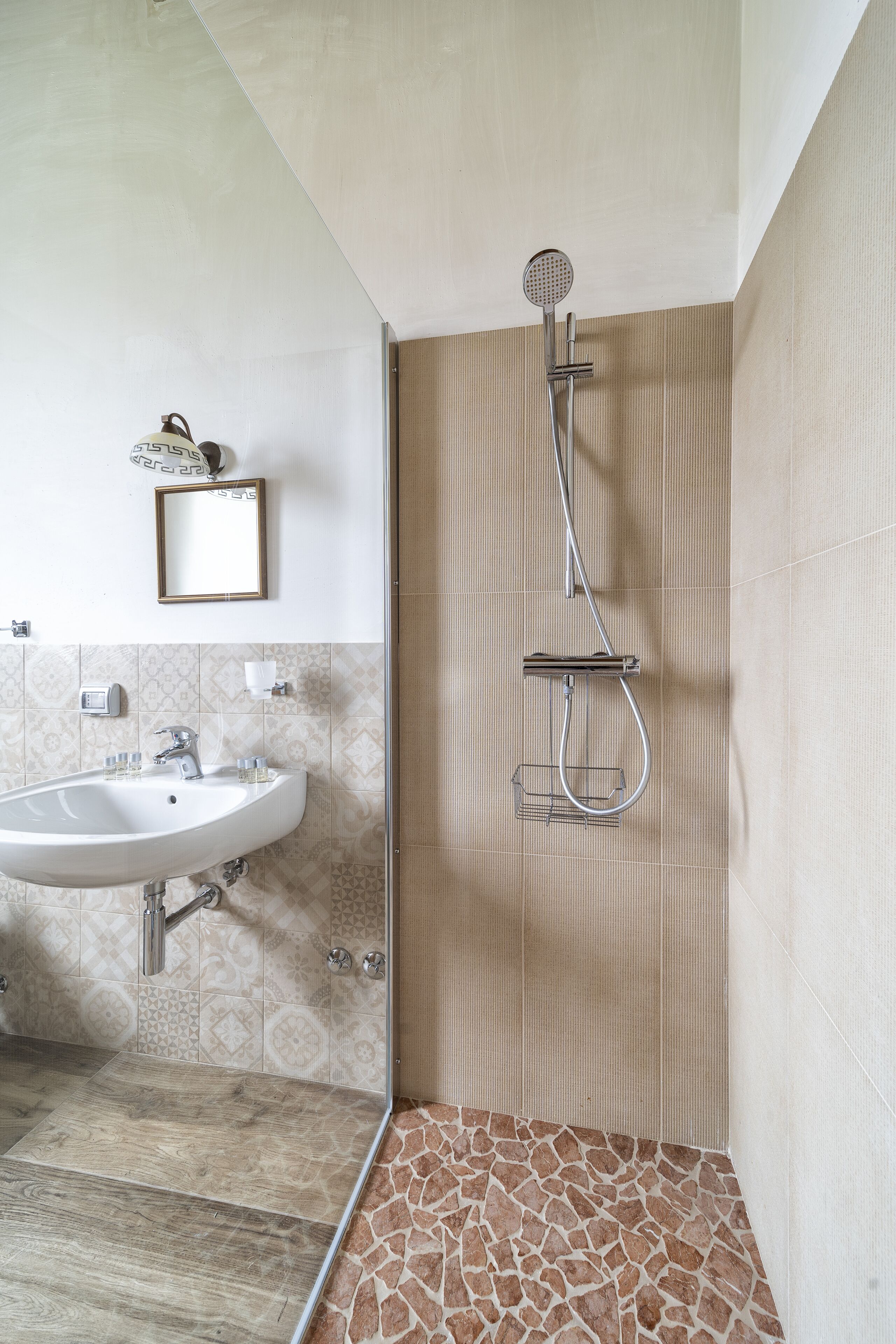 Een badkamer met een wastafel, spiegel en douche.