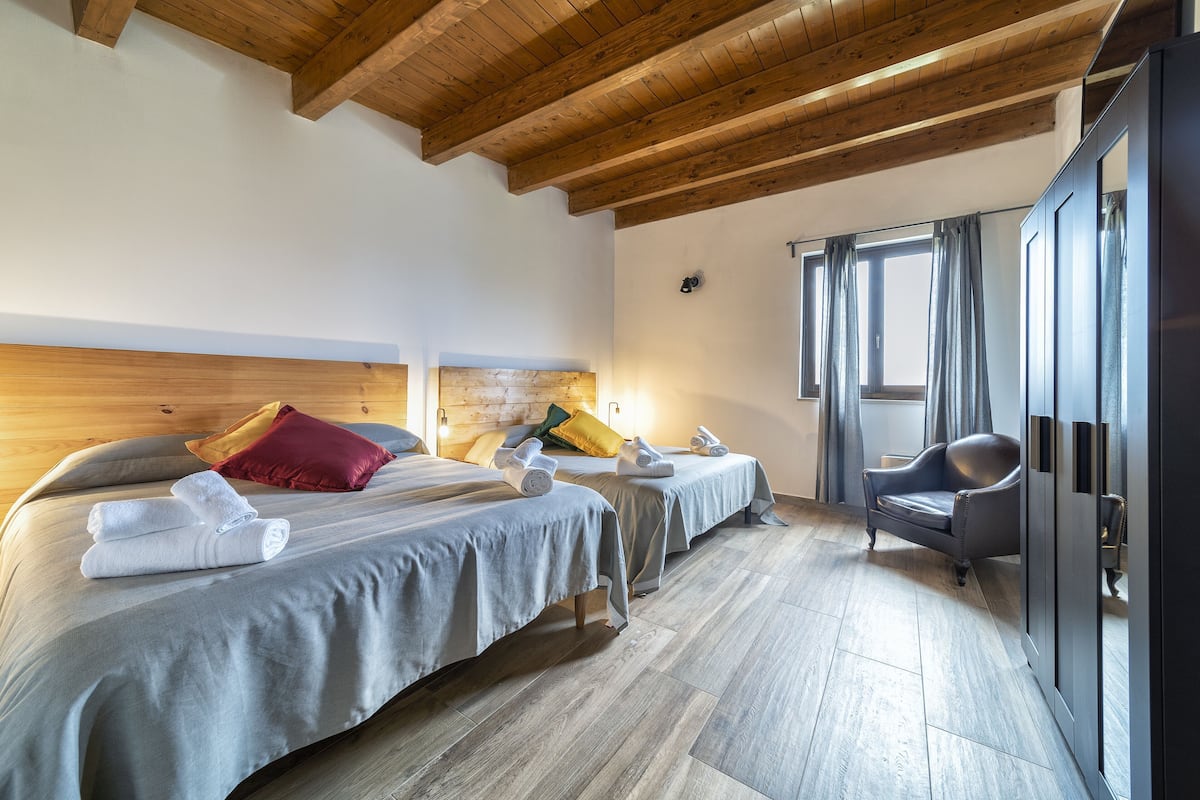 Habitación de hotel con dos camas, vigas de madera en el techo, una silla y un armario.