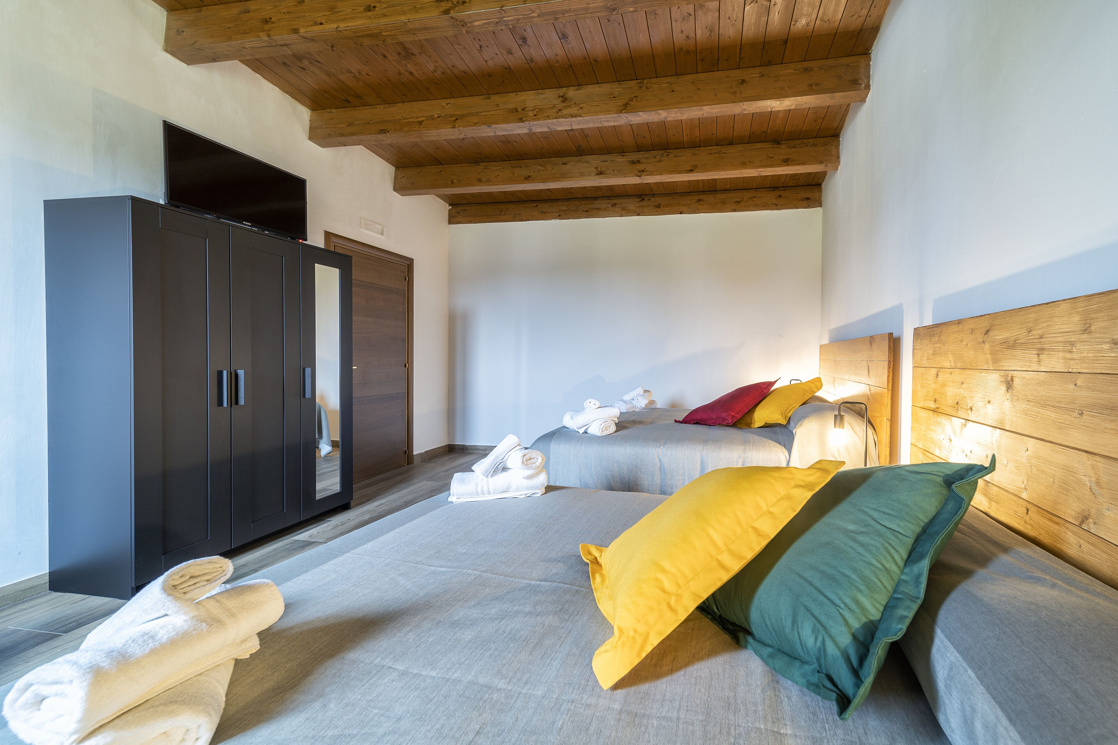 A bedroom with a bed, a wardrobe, and a flat-screen TV.