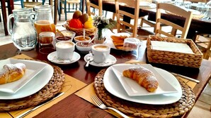 Een ontbijttafel met croissants, koffie en fruit.