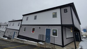 Un immeuble à plusieurs étages, avec une enseigne en forme de « B », une porte bleue et une pancarte indiquant « BUREAU OUVERT ».