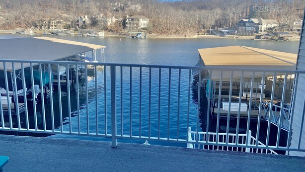 Une vue sur le front de mer depuis un balcon, avec des bateaux amarrés, un ciel dégagé et des maisons en arrière-plan.