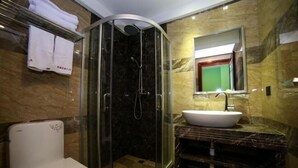 A modern bathroom with a glass-enclosed shower, a white toilet, a marble sink, and a mirror above the sink.
