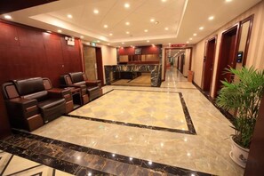 A hotel lobby with leather seating, a reception desk, and a marble floor.