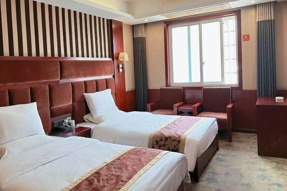 Une chambre d’hôtel avec deux lits, un bureau et une chaise.