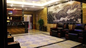A lobby with a check-in counter, seating area, and a large mural. - Tianmen Business Hotel (Zhangjiajie)