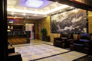 A lobby with a check-in counter, seating area, and a large mural. - Tianmen Business Hotel (Zhangjiajie)