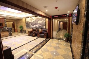 Eine Lobby mit Marmorboden, einer Rezeption, einer Sitzecke und einem großen Wandgemälde.