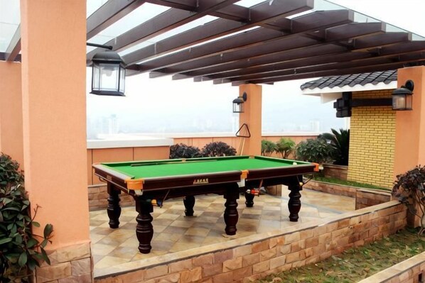 Une table de billard installée dans un espace extérieur, sous une pergola.