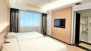 A hotel room with two beds, a TV mounted on the wall, and a wardrobe with a mirror.