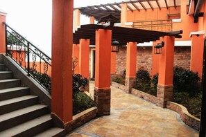 A covered outdoor area with a staircase leading to a building entrance, stone pillars, and a tiled floor. - Tianmen Business Hotel (Zhangjiajie)