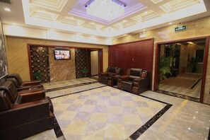 Eine Lobby mit Schachbrettmuster-Bodenbelag, einer Sitzecke, einem Fernseher und einer Rezeption.
