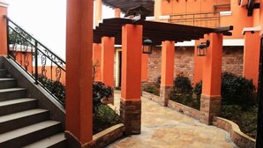 A covered outdoor area with stone pillars, a stone staircase, and a pergola.