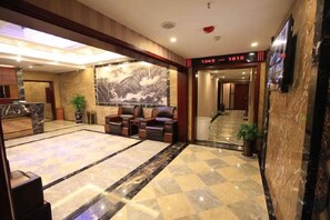 Vestíbulo de hotel con mostrador de recepción, zona de estar y un mural grande en la pared.