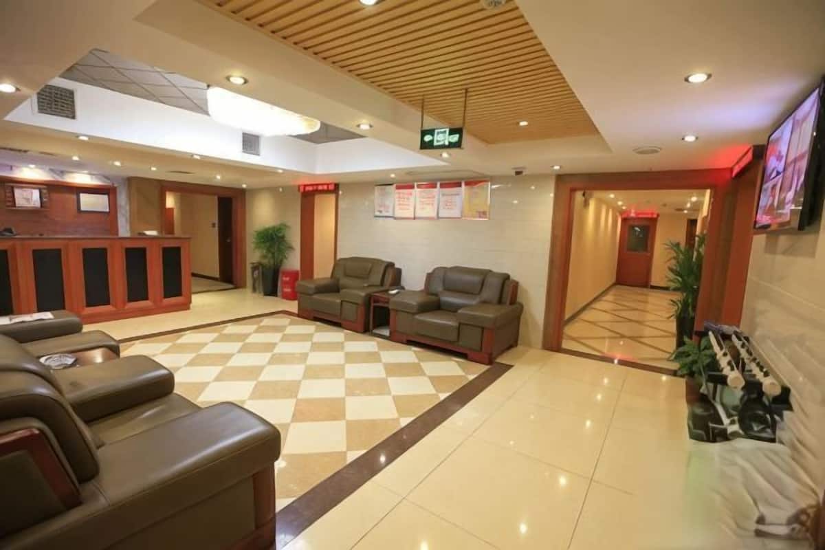 A hotel lobby with a reception desk, seating area, and a checkered floor.