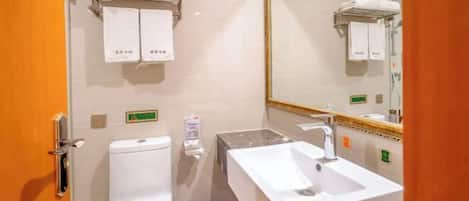 A bathroom with a toilet, sink, and mirror. There are towels hanging on the wall and a trash can.