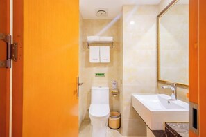 A bathroom with a toilet, sink, and mirror. - Langman Xicheng Hotel (Harbin)