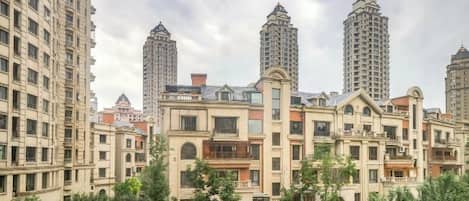 Un edificio residencial con varios apartamentos altos, un patio central y zonas verdes circundantes.
