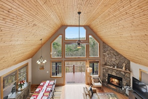 Un loft amplio con techo alto, ventanas grandes, chimenea de piedra y comedor.